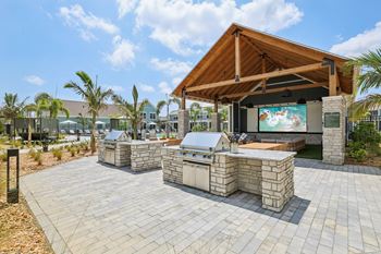A patio with a stone table and a wooden roofed pavilion at The Junction at Rockledge Apartments, Rockledge